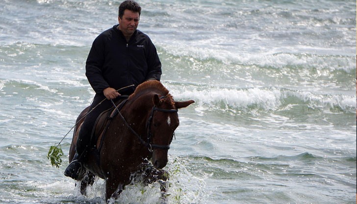 Жокеят влиза в морето с коня, за да го охлади след тренировка