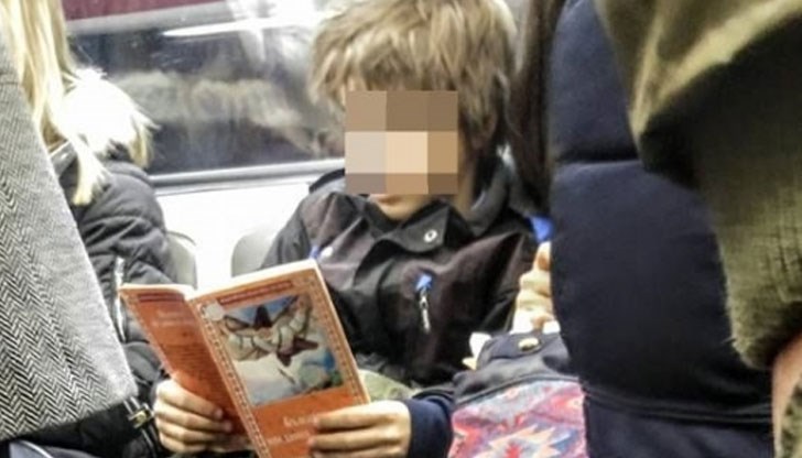 Детето чете книга, вместо да се взира в екрана на телефона си