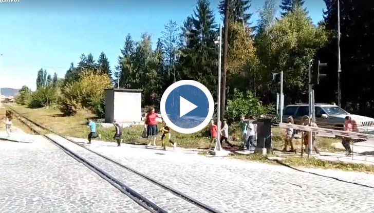 Децата претичват през линията, а влакът наближава