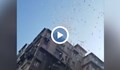 Мъж хвърля пачки пари от покрива на блок