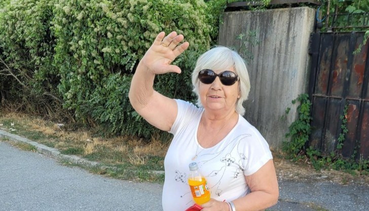 Жената е облечена с лилава блуза и клин и е по чехли