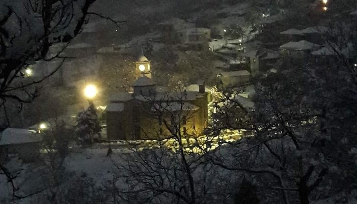 Любителско видео показва как снегът се сипе тихо на фона на коледната украса по улиците и домовете на хората