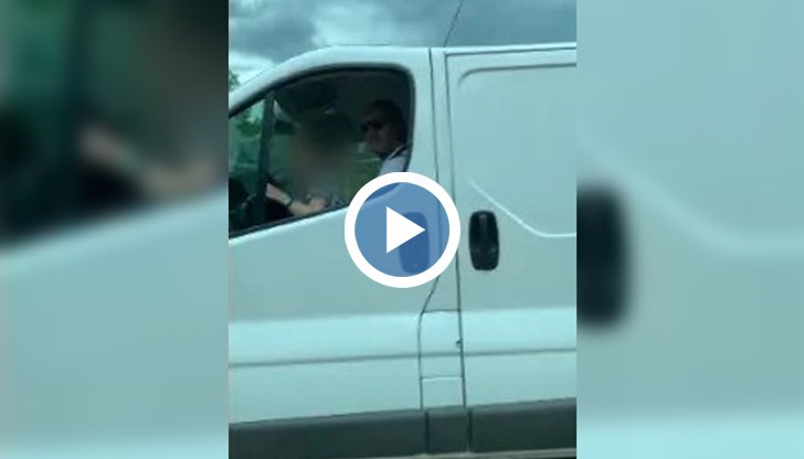 Мъж държи в скута си малко дете, докато шофира по оживен столичен булевард