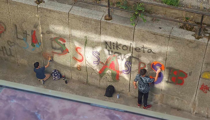 Две момчета показват творческите си умения на стена зад жилищен блок в центъра на града