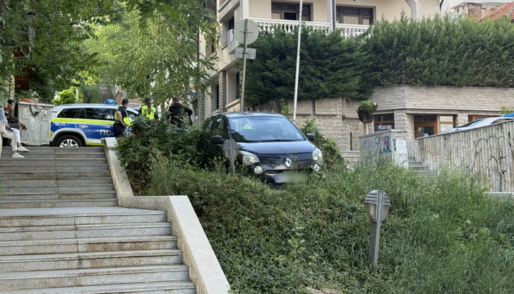 Автомобилът е спрял в зелената площ до стълбите при сградата